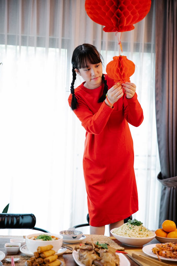 Services A young woman decorates for Lunar New Year with red lanterns, preparing a festive feast.